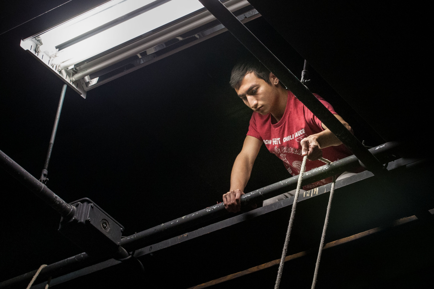 A student holds a rope in the Studio Theatre grid