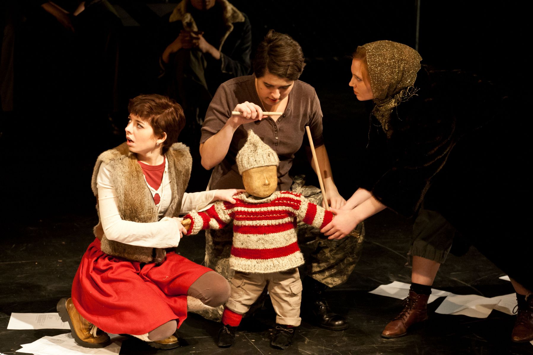 Three students manipulate a puppet in a production of The Caucasian Chalk Circle