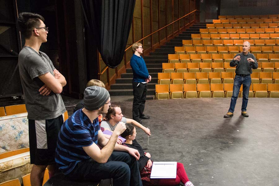 A faculty director gives notes to students on stage