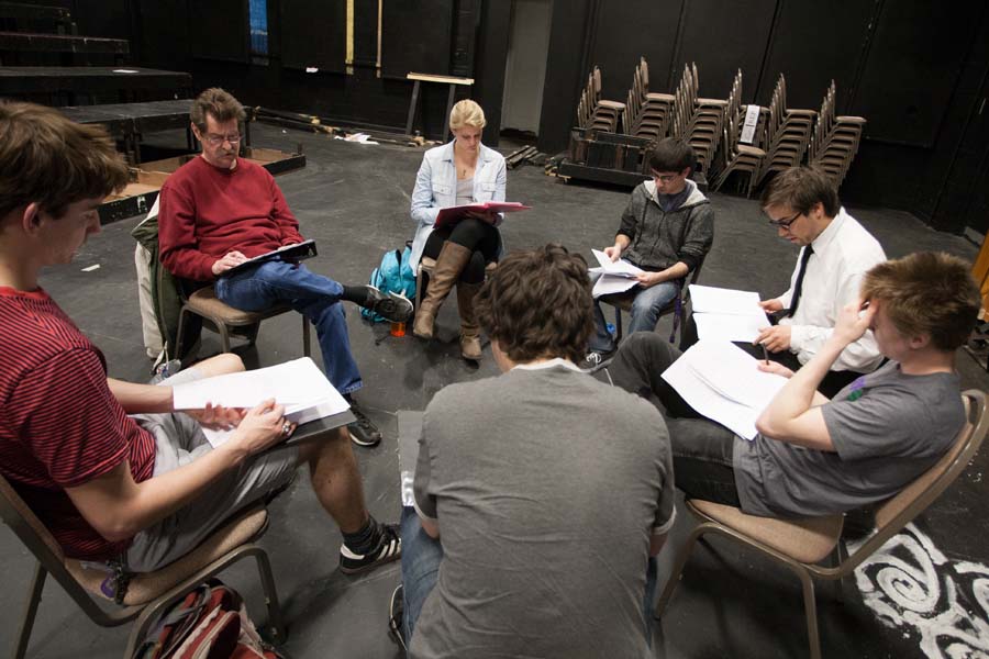 six students sit in a circle with a playwriting professor reviewing a script