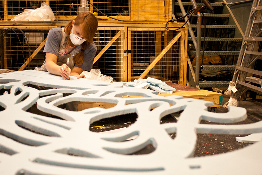 a worker carves sheet foam into a design