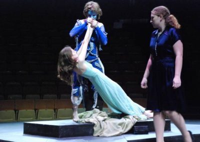 a man slowly lowering a woman down to the ground holding her hands, another woman standing nearby watching