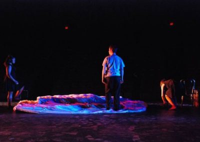 a man talks to a woman in colorful light while another woman dances by on their right