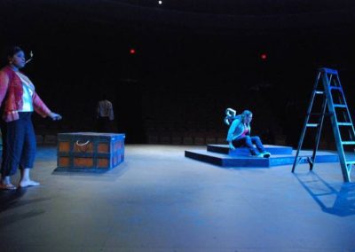 a woman walking stage right, a woman sitting on a platform center
