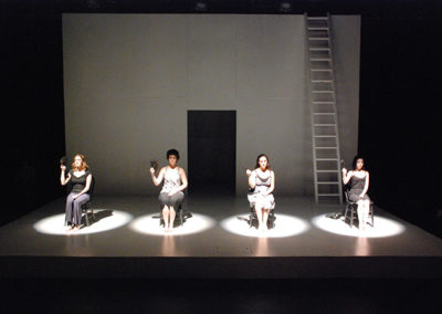 four women sitting in chairs holding folding fans, each in their own spotlight