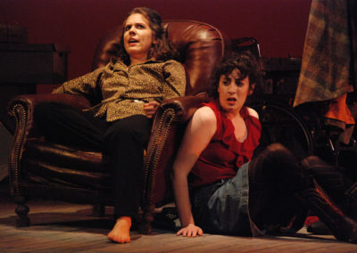 a woman sits in an old leather chair talking to another woman who is sitting on the floor and leaning on the chair