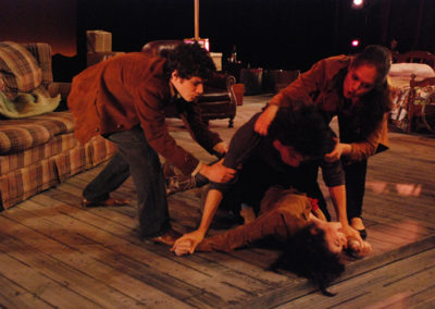 a man and a woman try to stop a fight between another man and a woman, the second man is attacking the second woman who is lying on the ground