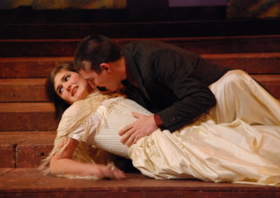 a man and a woman lay on the floor together, he is making romantic advances while she is grimacing and looking away