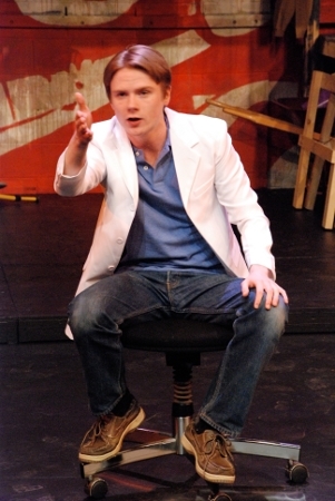 a man sitting and gesturing towards the audience