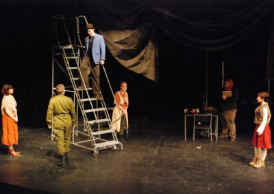 man standing on a rolling stair unit, five people stand on the floor talking to him