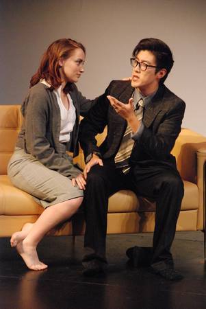 a man and a woman sitting on a couch talking, the man is gesturing and the woman has her hand on his shoulder