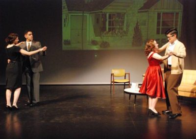 two couples dancing, projected image of a house on backdrop