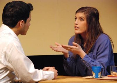 two people sitting and talking, woman has her hands up and gesturing to the man