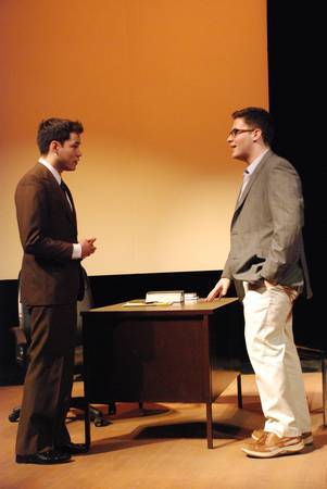 two men standing and talking over a desk