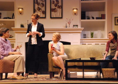 four women with martinis talking in a living room, three women sitting and one woman standing