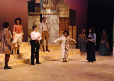 eight people on stage, one man standing center, about to bow