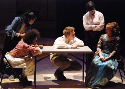 four people interrogating a woman sitting at a table