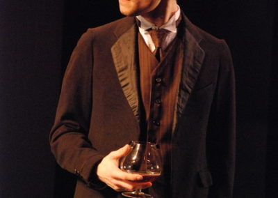 man standing, holding brandy snifter