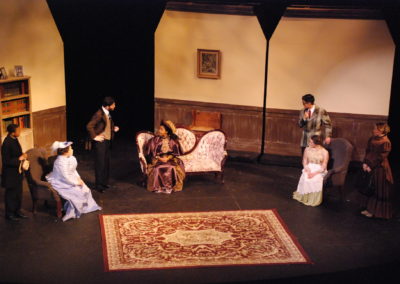 six people sitting and standing, talking inside a country home