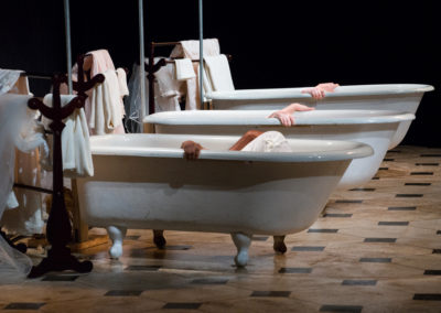 the hands of three women clutching the sides of each of three bathtubs, faces and bodies hidden from view