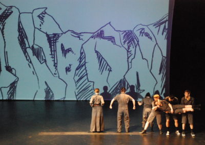 3 people holding a person horizontal facing forward, three people standing facing upstage, sketched image of a mountain projected on backdrop