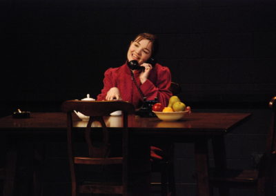 woman sitting at table, talking on the telephone